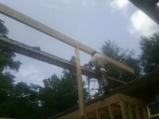 Carpenter setting a ridge beam over a new addition frame — Ice Dam Removal by Roofing Brothers in Ruffin