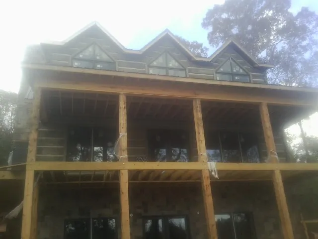 Dormers and porch framing on a large log home under construction — Roof Coating work by our crew in Ruffin
