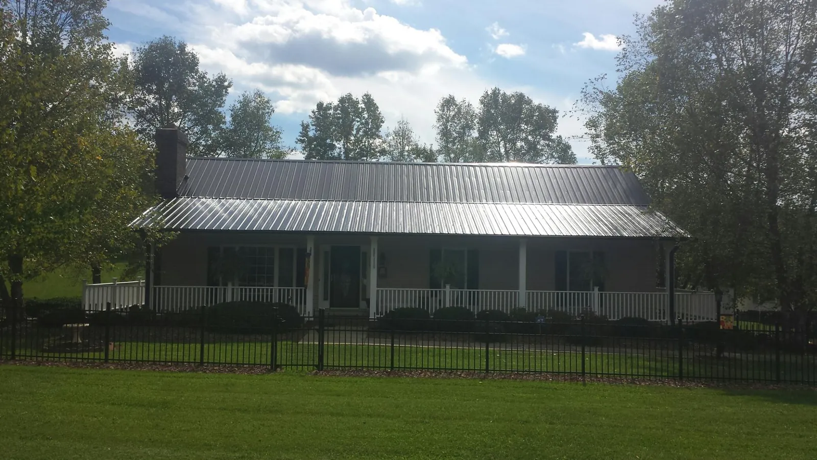 Gray metal roof on a brick ranch with a full width front porch — Gutter Guard Installation work by our crew in Ruffin